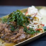 Steak with herb salad / greens (possibly chimichurri-style topping)
