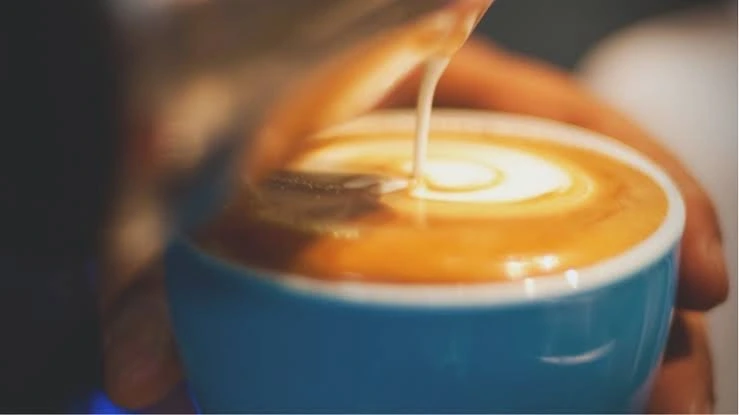 Barista pouring steamed milk for latte art: Best specialty coffee Singapore.