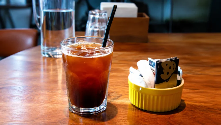Glass of iced black coffee with a straw featuring Cold Brew Coffee in Singapore cafes.